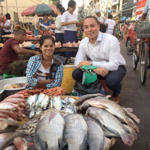 2 People posing next to Fish at a market in Myanmar