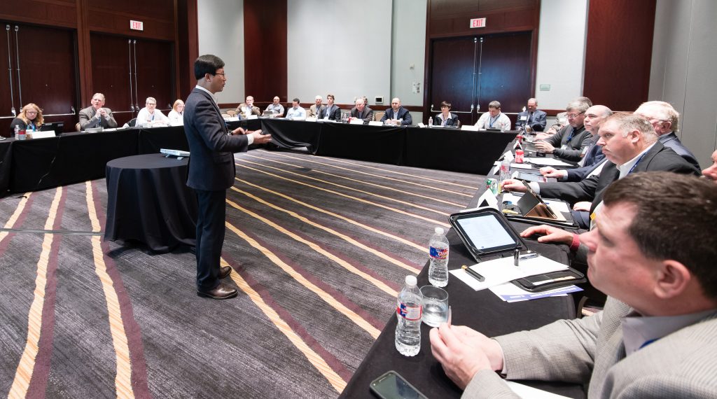 A man speaking to a large group of people in a conference room