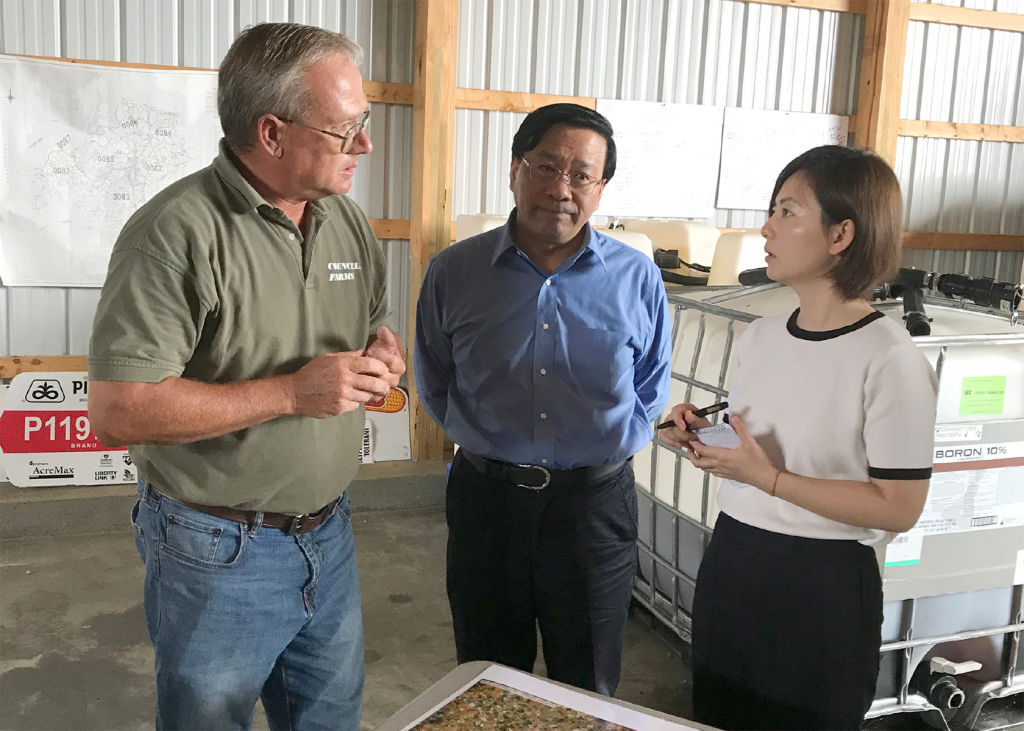 two members of a Chinese delegation speaking with Chip Councell of Councell Farms