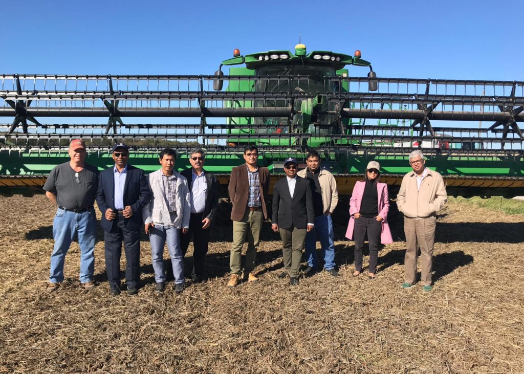 South Asia Trade Team standing in front of a combine harvester