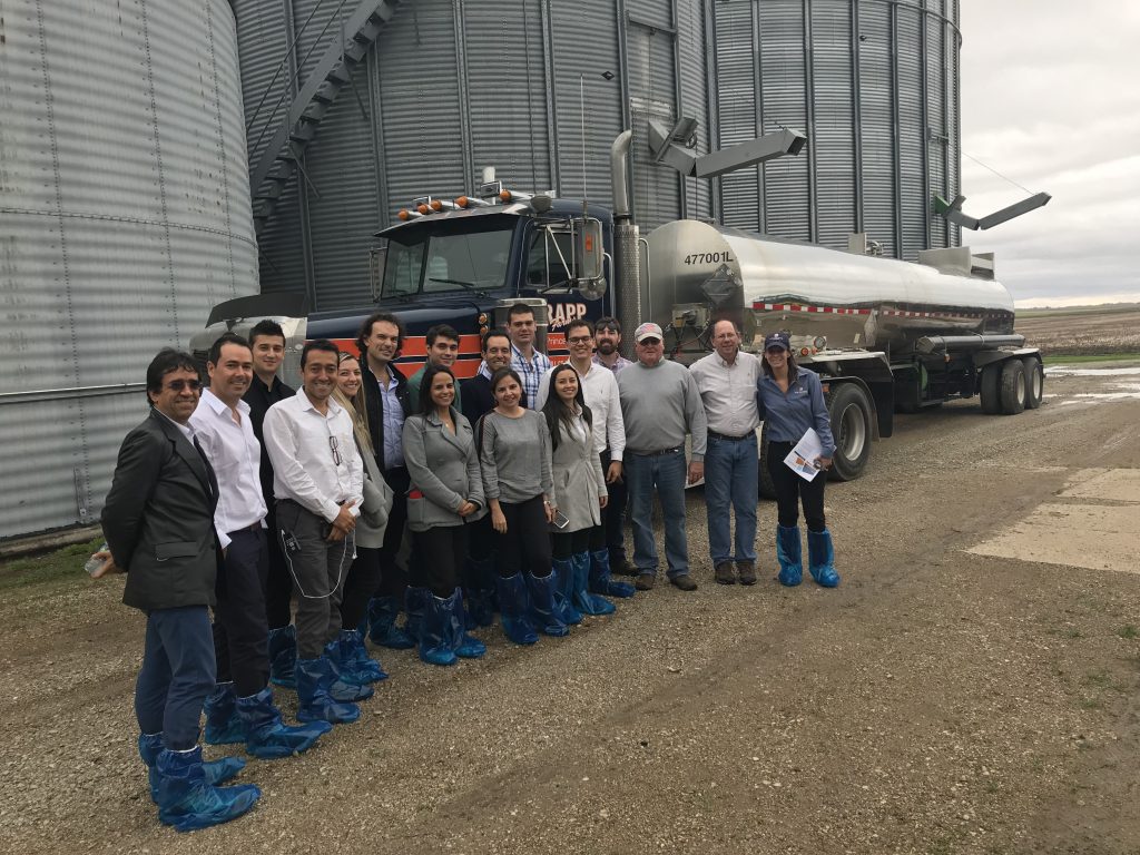 poultry team at farm visit- group photo of team standing in front of farming equipment