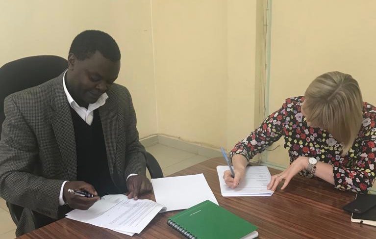 Kenya MOU signing- man and woman seated at table signing documents