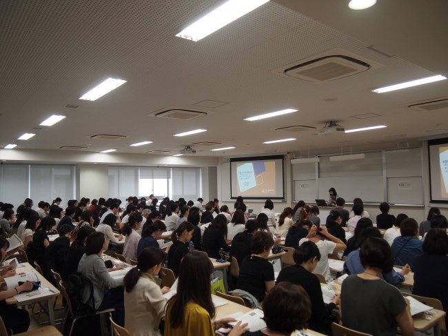 Japanese Food Sorghum Promotion- aerial view of attendees listening to a woman speaking at a podium