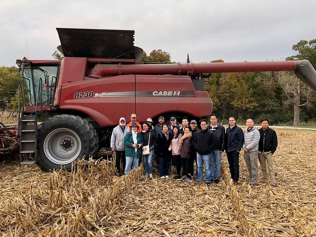 SEA ExEx Team- group photo of team members standing in front of farm equipment in a field of corn