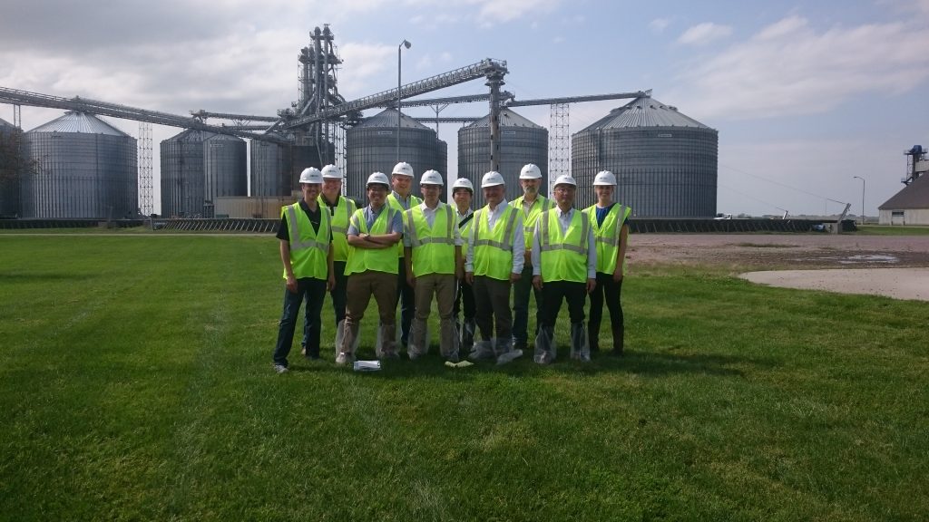 Japan Feed Corn Team- group photo of team members standing in front of ethanol plant