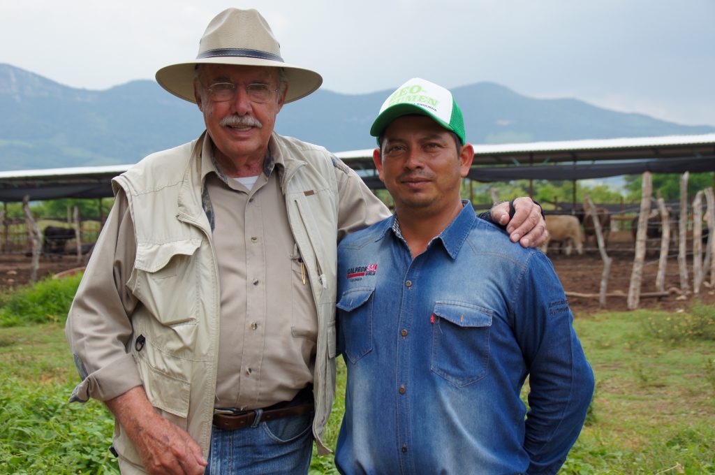 Working with DDGS Suppliers in SE Mexico- 2 men standing in a field with cattle behind them