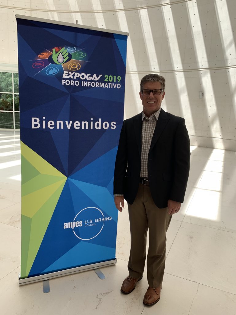 a man standing beside a banner for the 2019 AMPES Workshop