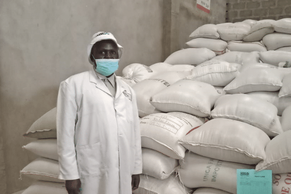 Man Standing In Front of Bags of Flour