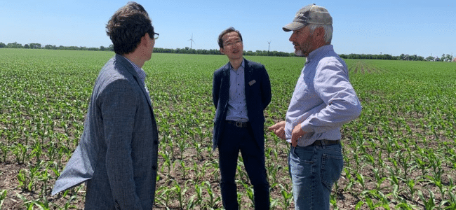 Man Speaking to Two Other Men in Field