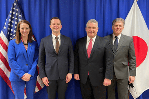 four people standing in front of a US and Japan flag