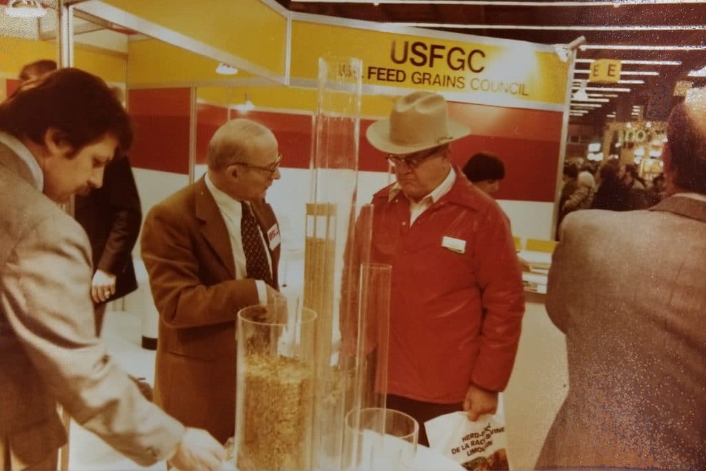 an old photo of a group of men at a trade show talking