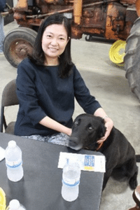 image of a woman smiling with a black dog