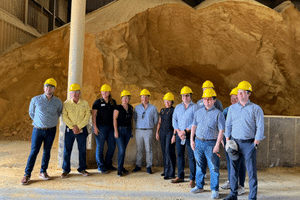 a group of people wearing hard hats in front of a pile of DDGS