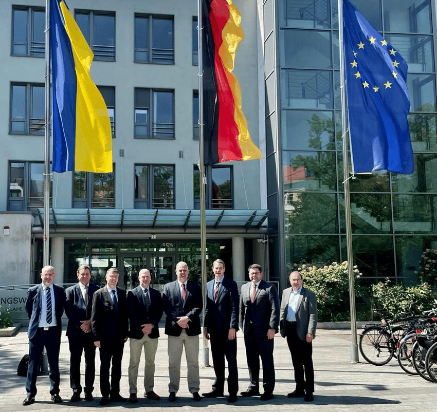 image of a group of men in suits standing in front of three flags