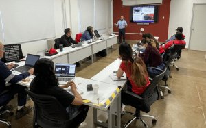 image of people at a conference room table listening to a presentation
