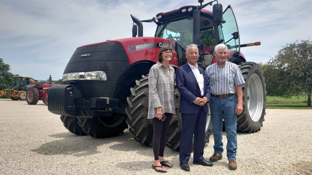 image of three people posing in front of a tractor