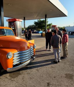People at a gas station looking at a vintage car