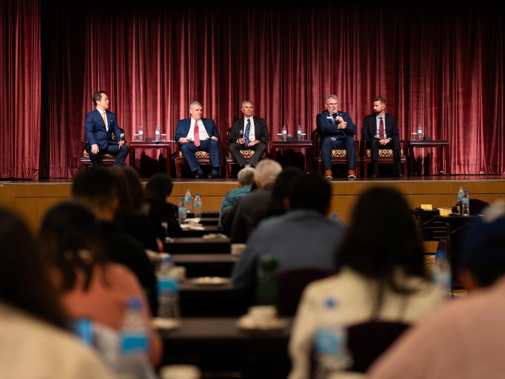 image of five men on a panel at a conference