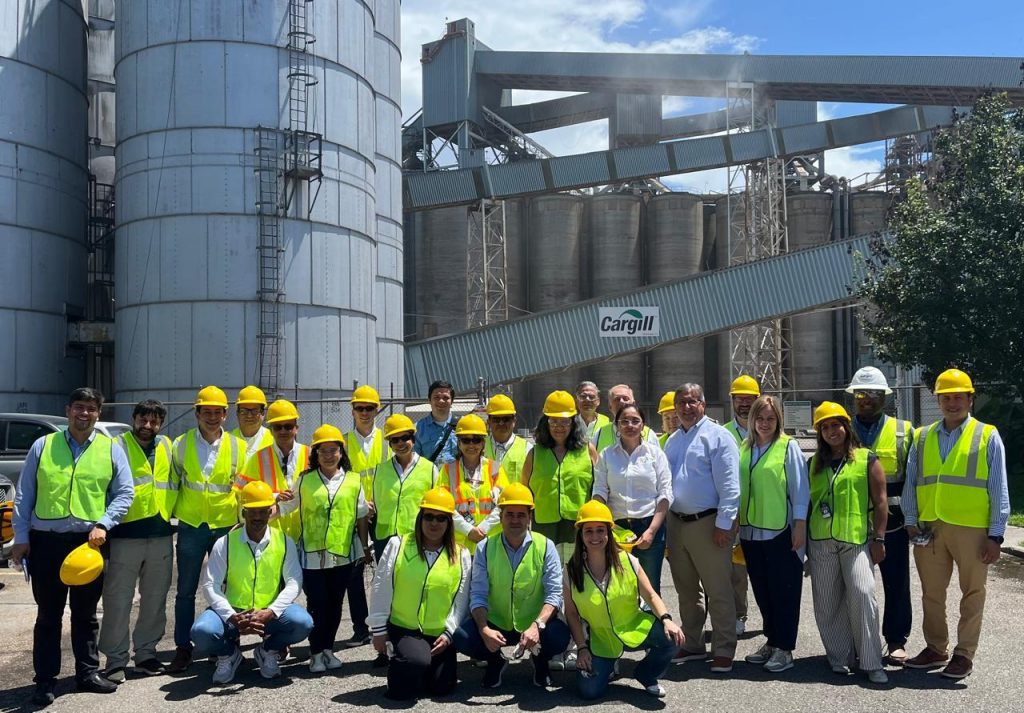 A group of people in safety gear in front of a grain elevator