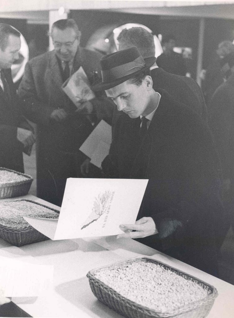 A black and white photo of a man reading a pamphlet